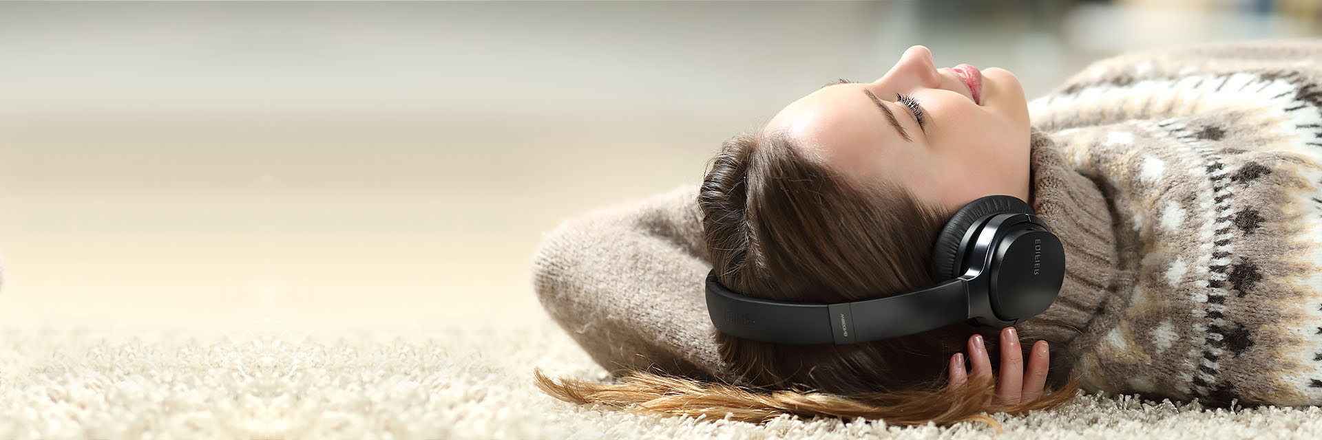 A girl is lying on the ground listening to music with Edifier W860NB noise-cancelling headphone